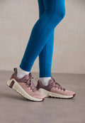 Sportliche Schuhe in Hellrosa und Beige mit strukturierten Seitenpaneelen, braunen Akzenten und flexiblen Sohlen. Getragen mit blauen Leggings und weißen Socken.