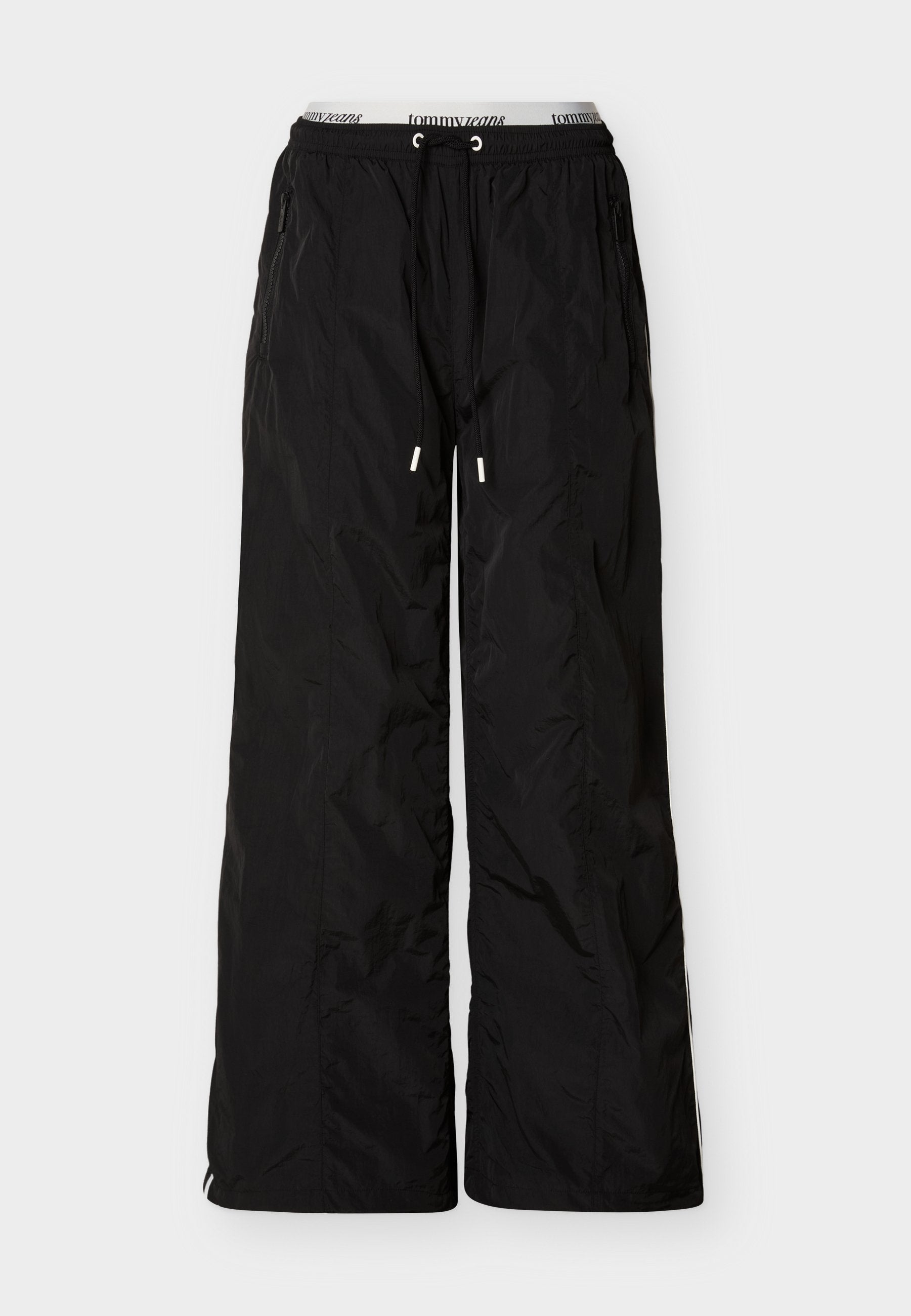 Schwarze, locker sitzende Nylonhose mit elastischem Bund und Kordelzug, seitlichen Reißverschlusstaschen und sichtbarem Tommy Jeans Marken-Innenbund.