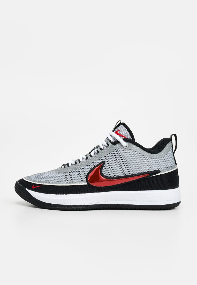 Grauer und schwarzer Low-Top-Sneaker mit weißen Schnürsenkeln und rotem Nike Swoosh-Logo an der Seite und nahe der Zehen, dargestellt vor weißem Hintergrund.