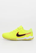 Hellgelber Nike Sportschuh mit schwarzem und orangefarbenem Swoosh-Logo und strukturierter Sohle, von der Seite auf weißem Hintergrund gezeigt.
