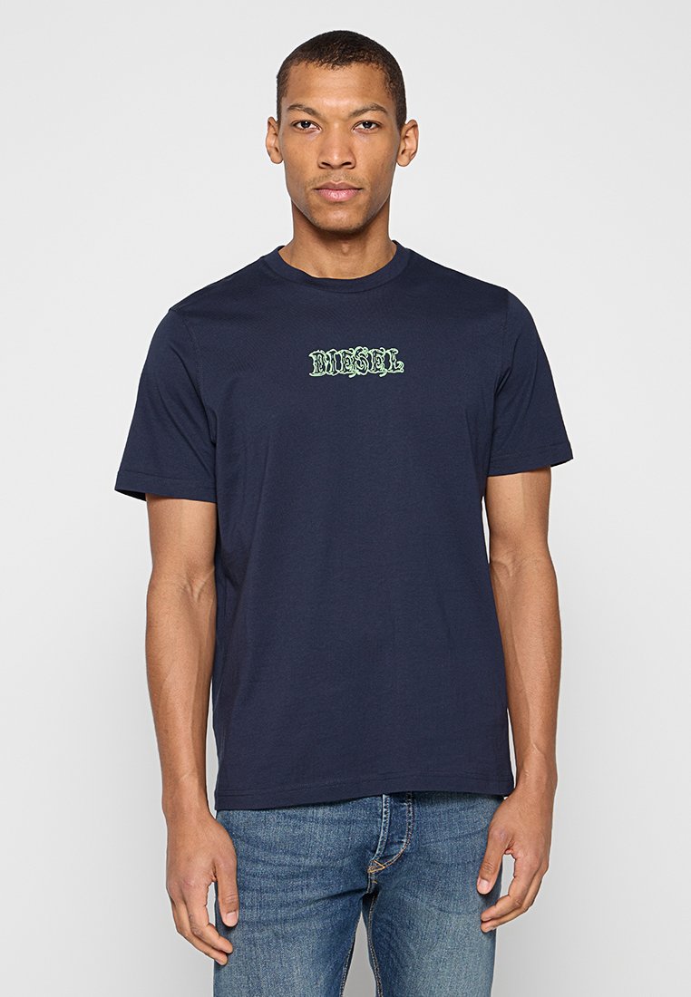 Marineblaues Baumwoll-T-Shirt mit einem strukturierten grünen "DIESEL"-Logo auf der Brust. Standardpassform mit kurzen Ärmeln und Rundhalsausschnitt.