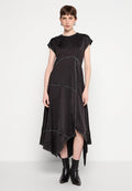 Schwarzes Satin-Kleid mit lässiger Passform, kurzärmeligen Cap-Ärmeln, asymmetrischem Saum und kontrastierenden Nähten. Getragen mit schwarzen Knöchelstiefeln.