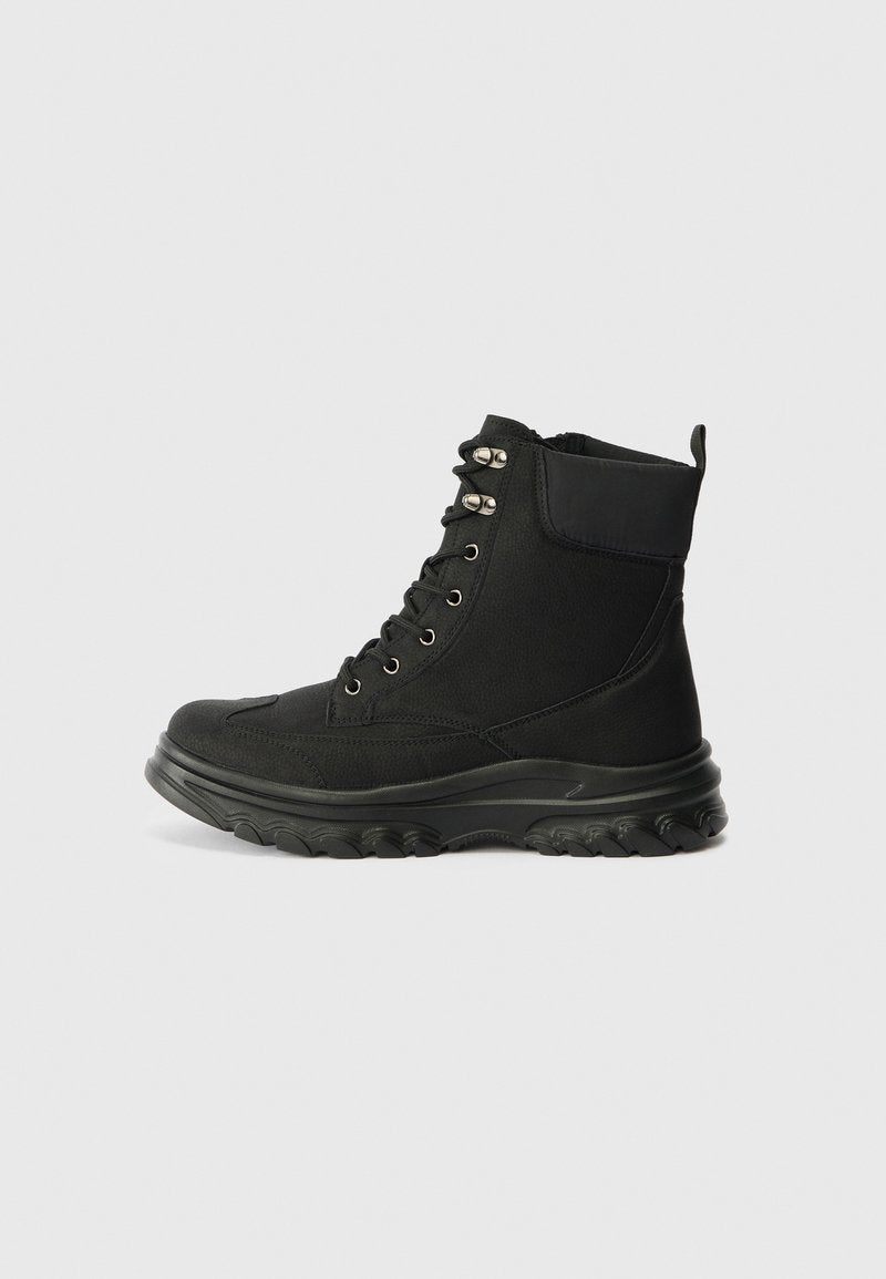 Schwarze Wanderschuhe mit einem Obermaterial aus strukturiertem Stoff, Gummisohle, metallischen Ösen und gepolstertem Schaftrand. Mit einer Zuglasche an der Ferse.