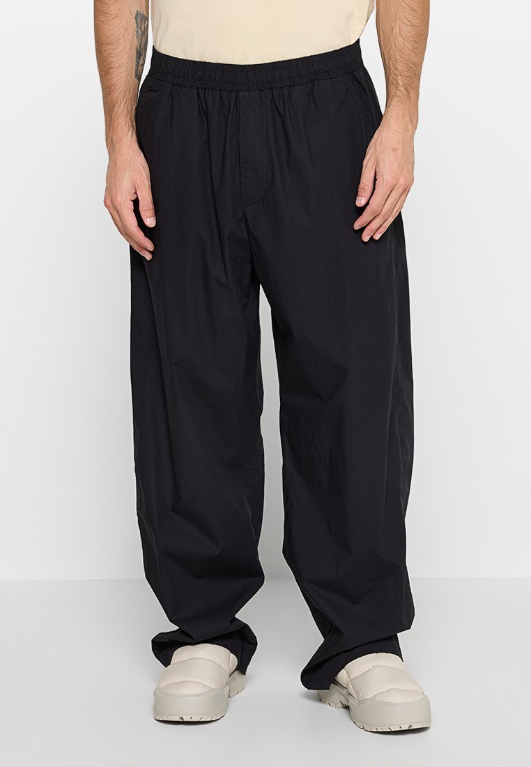 Schwarze, locker sitzende Hose mit elastischem Bund, aus leichtem Material gefertigt, mit Seitentaschen und einer weichen Textur.