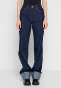 Dunkelblaue Denim-Weitbeinjeans mit hoher Taille, mit vorderen Taschen und einem umgeschlagenen Saum, der ein helleres Blau zeigt. Getragen werden schwarze Schuhe.