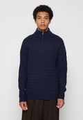 Marineblau gestrickter Pullover mit hohem Kragen und Viertel-Reißverschluss, der ein strukturiertes Muster sowie gerippte Bündchen und Saum aufweist.