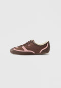 Brauner Sneaker mit niedrigem Schaft, pinkfarbenen Verzierungen, Schnürsenkeln und "HUGO"-Logo an der Seite, vor einem schlichten hellen Hintergrund.