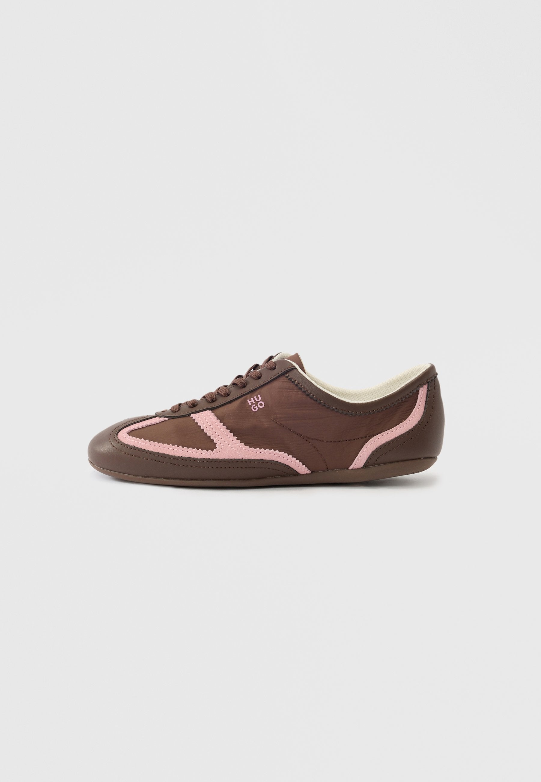 Brauner Sneaker mit niedrigem Schaft, pinkfarbenen Verzierungen, Schnürsenkeln und "HUGO"-Logo an der Seite, vor einem schlichten hellen Hintergrund.