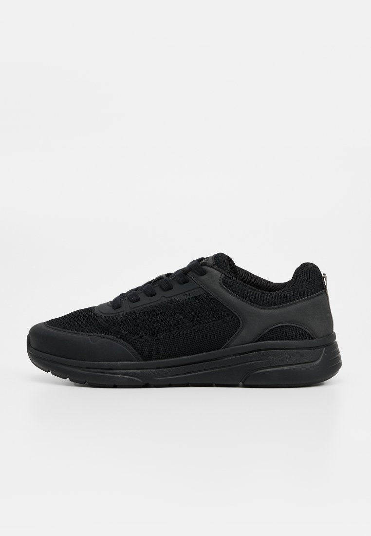 Schwarzer Sneaker mit niedrigem Schaft, Mesh- und synthetischem Obermaterial, Schnürverschluss und dicker Gummisohle, seitlich auf weißem Hintergrund dargestellt.