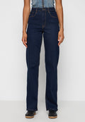 Dunkelblaue Denim-Jeans mit hoher Taille, geradem Bein, kontrastierenden orangefarbenen Nähten und Fronttaschen. Getragen mit schwarzen Schuhen.
