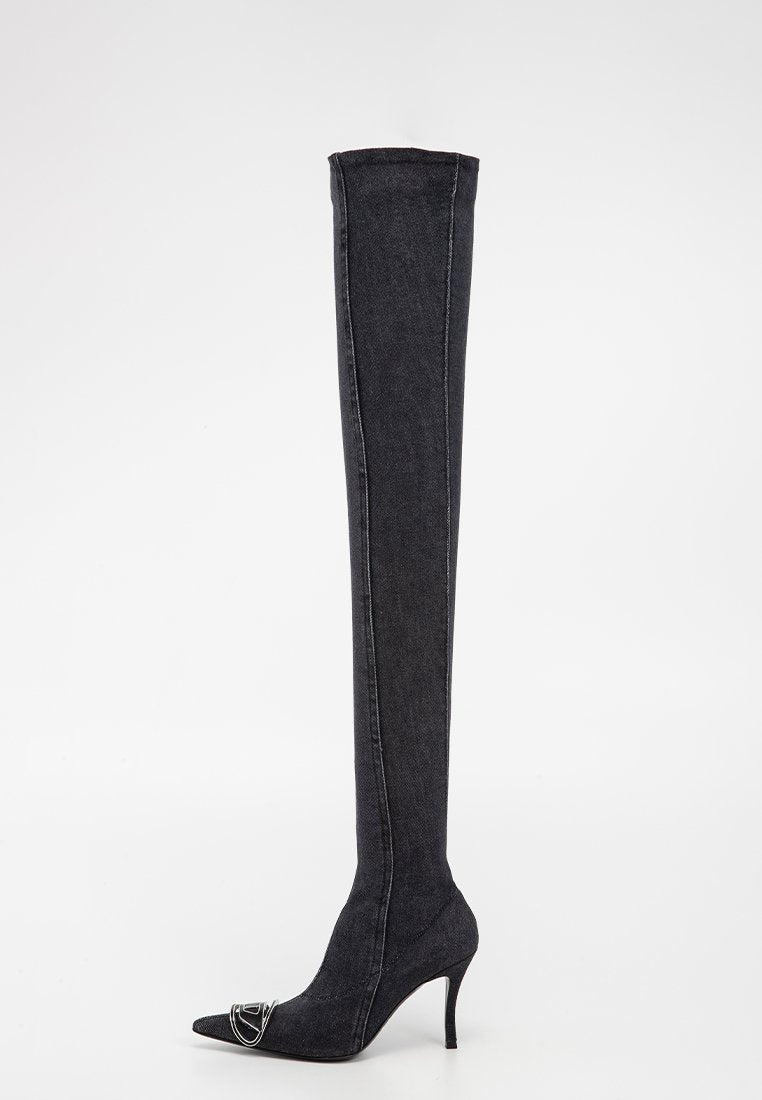 Schwarze, knöchelhohe Stiletto-Stiefel mit spitzer Zehe, schlankem hohen Absatz und silberner dekorativer Schnalle an der Zehe vor weißem Hintergrund.