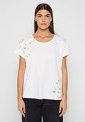 Weißes Baumwoll-T-Shirt mit kurzen Ärmeln, das auf der linken Seite ein ausgeschnittenes Blumenmuster zeigt. Rundhalsausschnitt und lockere Passform.