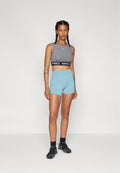 Grauer ärmelloser Crop-Top mit einem schwarzen "PRO"-Bund, kombiniert mit hellblauen engeren Shorts. Schwarze Sportschuhe vervollständigen das Outfit.