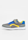 Grauer Kindersneaker aus Mesh mit blauen Schnürsenkeln, gelbem Seitenstreifen, grauem Klettverschluss, gepolstertem gelbem Kragen und weißer, profilierten Sohle.