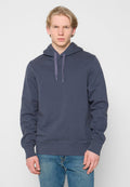 Marineblauer Hoodie aus Baumwollmischungen mit Kordelzugkapuze, gerippten Bündchen und geradem Saum. Kombiniert mit blauen Jeans.