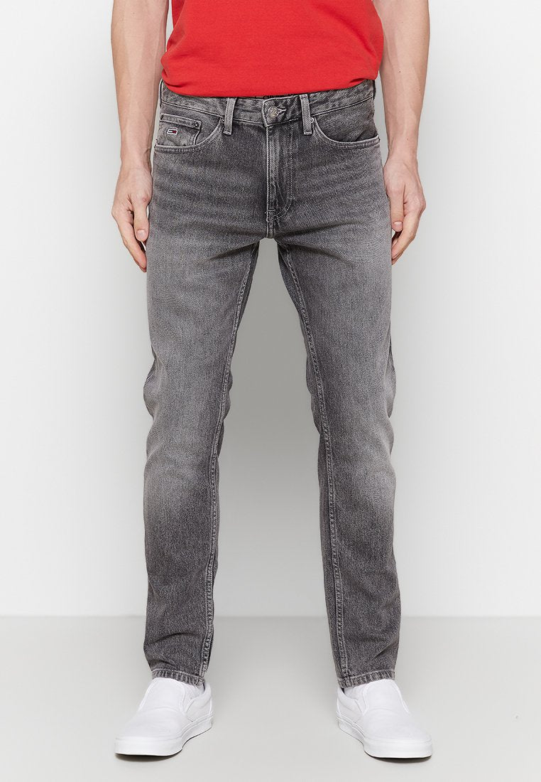 Herren Graue Denim-Jeans mit geradem Schnitt, ausgewaschenem Finish, Fünf-Taschen-Design und dezenten Nähten. Kombiniert mit weißen Schuhen.