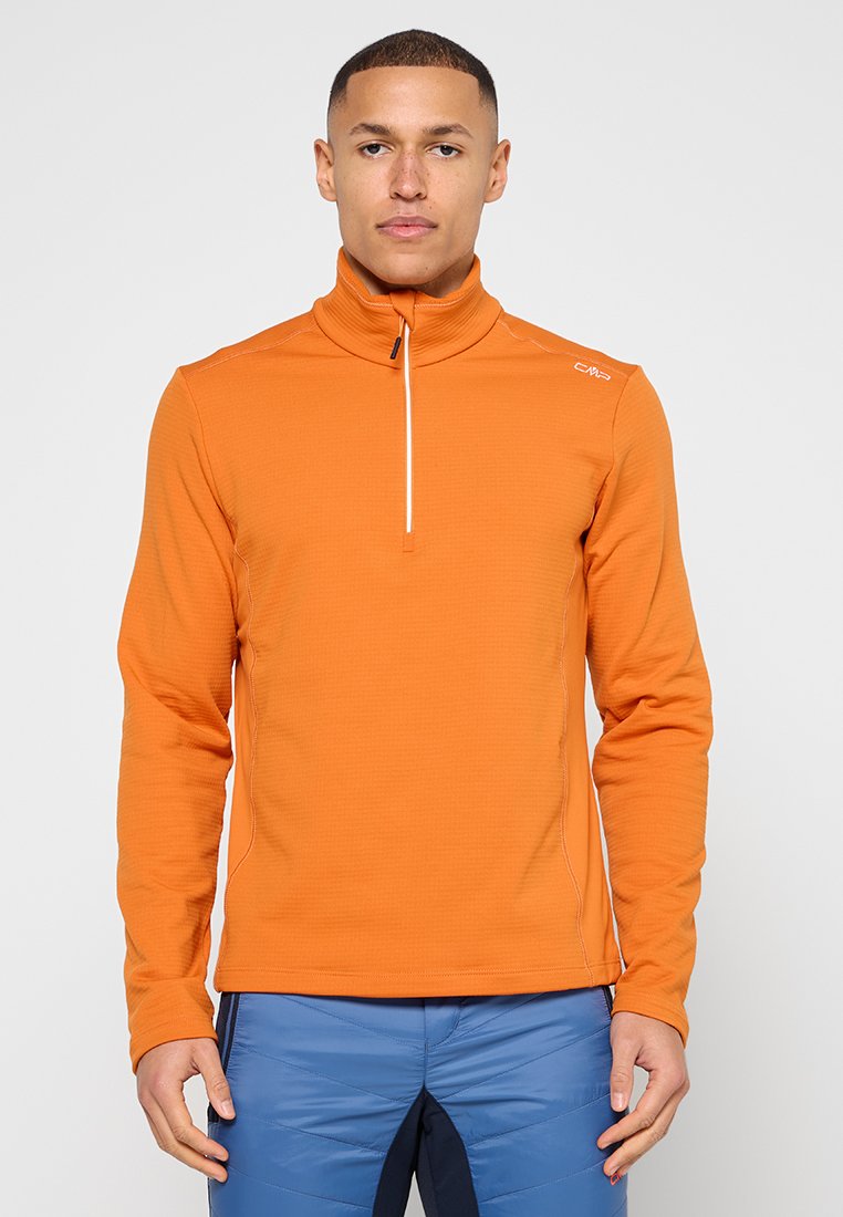 Oranges Langarm-Oberteil mit einem Viertel-Reißverschluss und einem strukturierten Muster, ausgestattet mit weißem Reißverschluss und Logodetail, kombiniert mit blauer Hose.