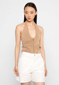 Beige Halter-Bodysuit mit gerafften Details und Reißverschluss vorne; kombiniert mit weißen bestickten Shorts für einen kontrastierenden Look.