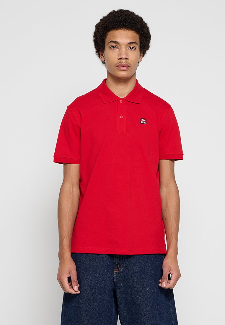Rotes Poloshirt aus Baumwolle mit klassischem Kragen, zwei Knöpfen und kleinem Logo auf der linken Brust. Kurze Ärmel, normale Passform.