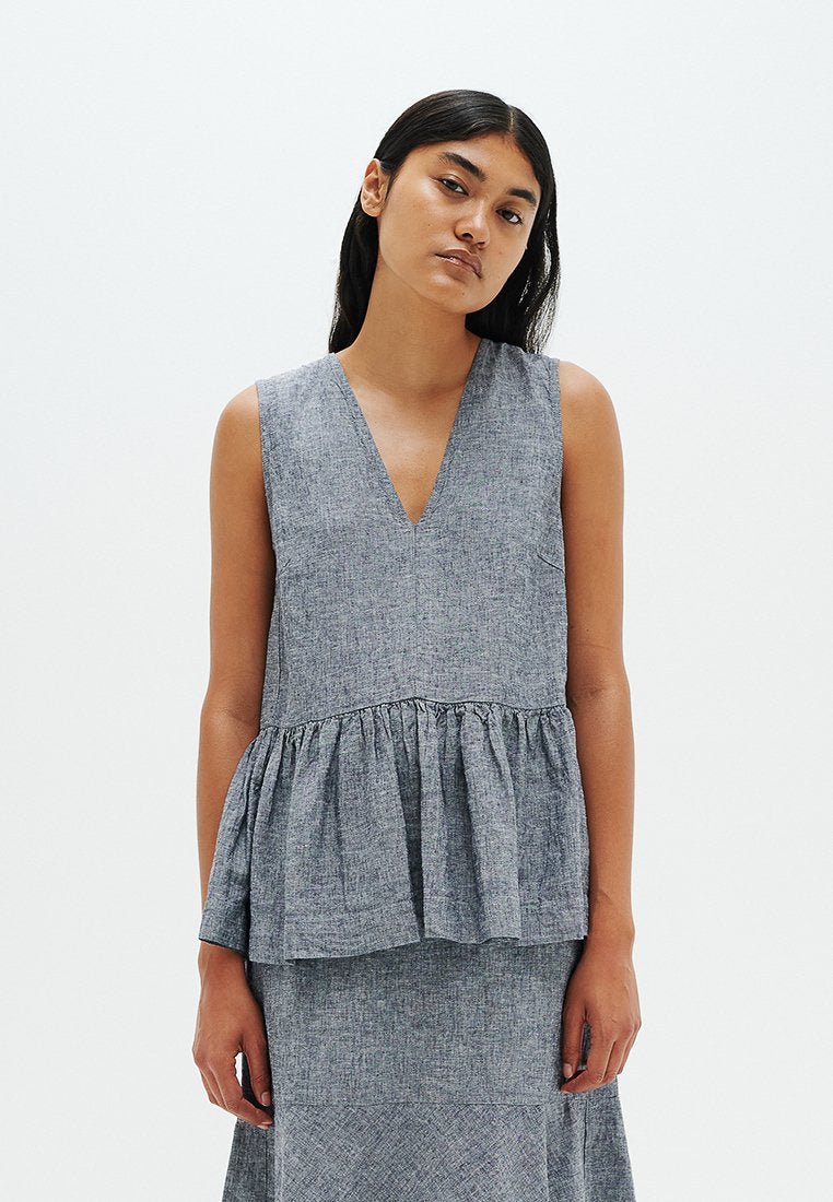 Grauer Peplum-Top aus leichtem Stoff mit tiefem V-Ausschnitt und geraffter Taille, das eine weiche Textur und klare Linien aufweist.