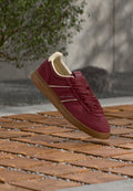 Bordeauxfarbener Sneaker mit cremefarbenen Akzenten, strukturiertem Stoff, flachen Schnürsenkeln und einer Gummisohle. Mit Markennamen an der Seite und an der Fersenschlaufe.
