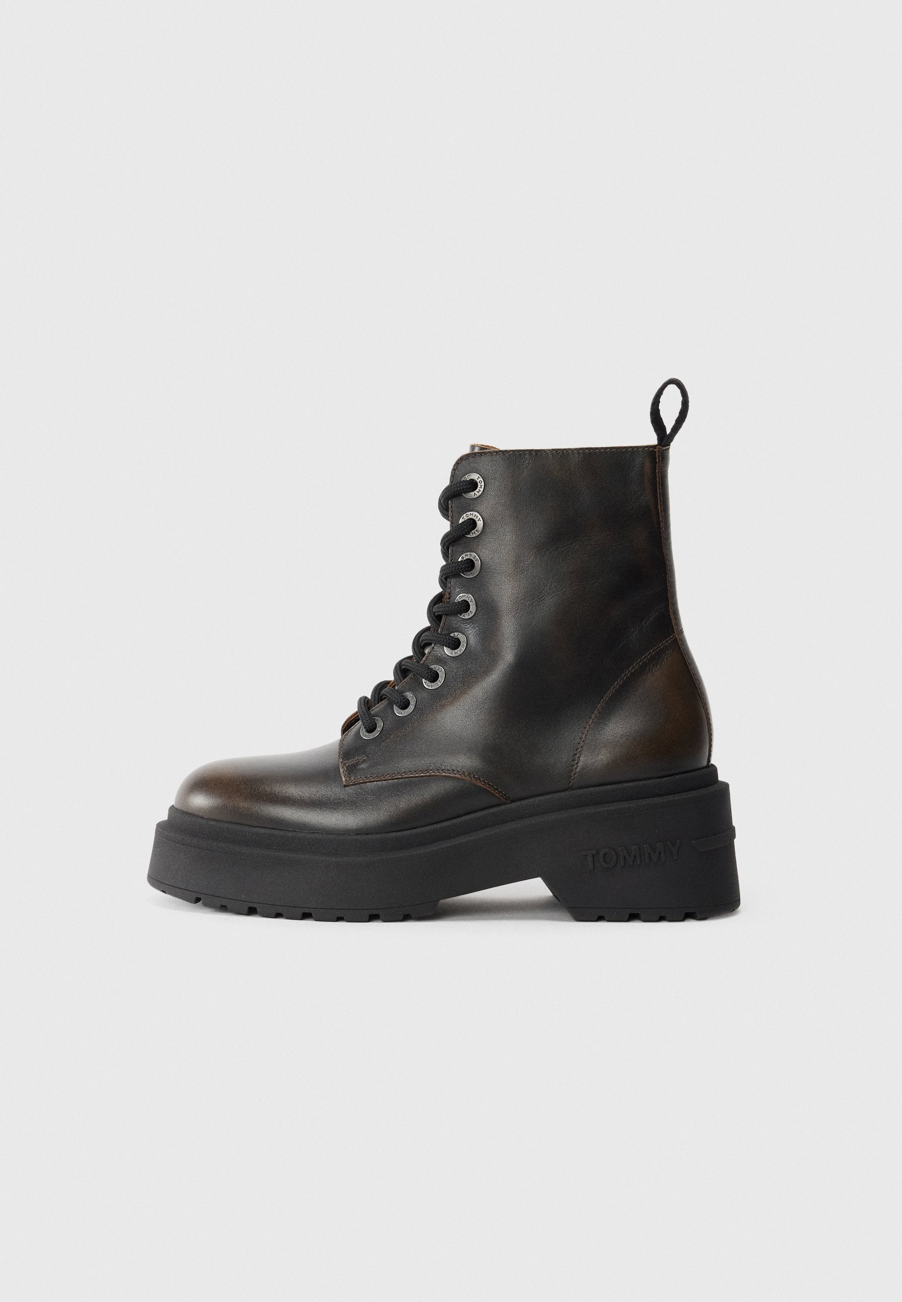 Schwarze Leder-Ankle-Boots mit Schnürung, dicke schwarze Sohle und einer Schlaufe auf der Rückseite, die den eingeprägten Markennamen an der Ferse zeigt.