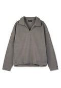 Grauer Fleece-Pullover mit Kragen, V-Ausschnitt und überschnittenen Schultern. Weiche Textur, lässige Passform und minimale Nähdetails.
