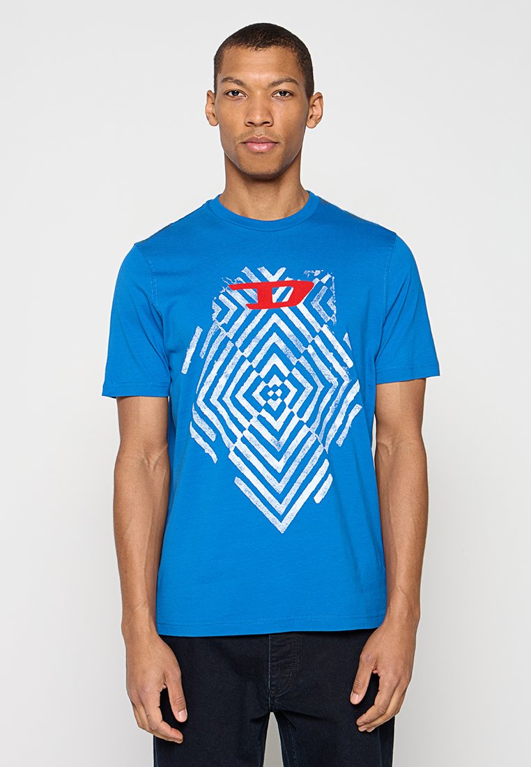 Blaues Baumwoll-T-Shirt mit einem geometrischen weißen Muster und einem roten grafischen Akzent auf der Brust. Kurze Ärmel und ein Rundhalsausschnitt.