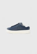 Marineblaue Leder-Low-Top-Sneaker mit schwarzen Schnürsenkeln, weiß gepolstertem Fersenkragen und dicker weißer Gummisohle auf hellgrauem Hintergrund.