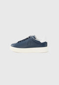 Marineblaue Leder-Low-Top-Sneaker mit schwarzen Schnürsenkeln, weiß gepolstertem Fersenkragen und dicker weißer Gummisohle auf hellgrauem Hintergrund.
