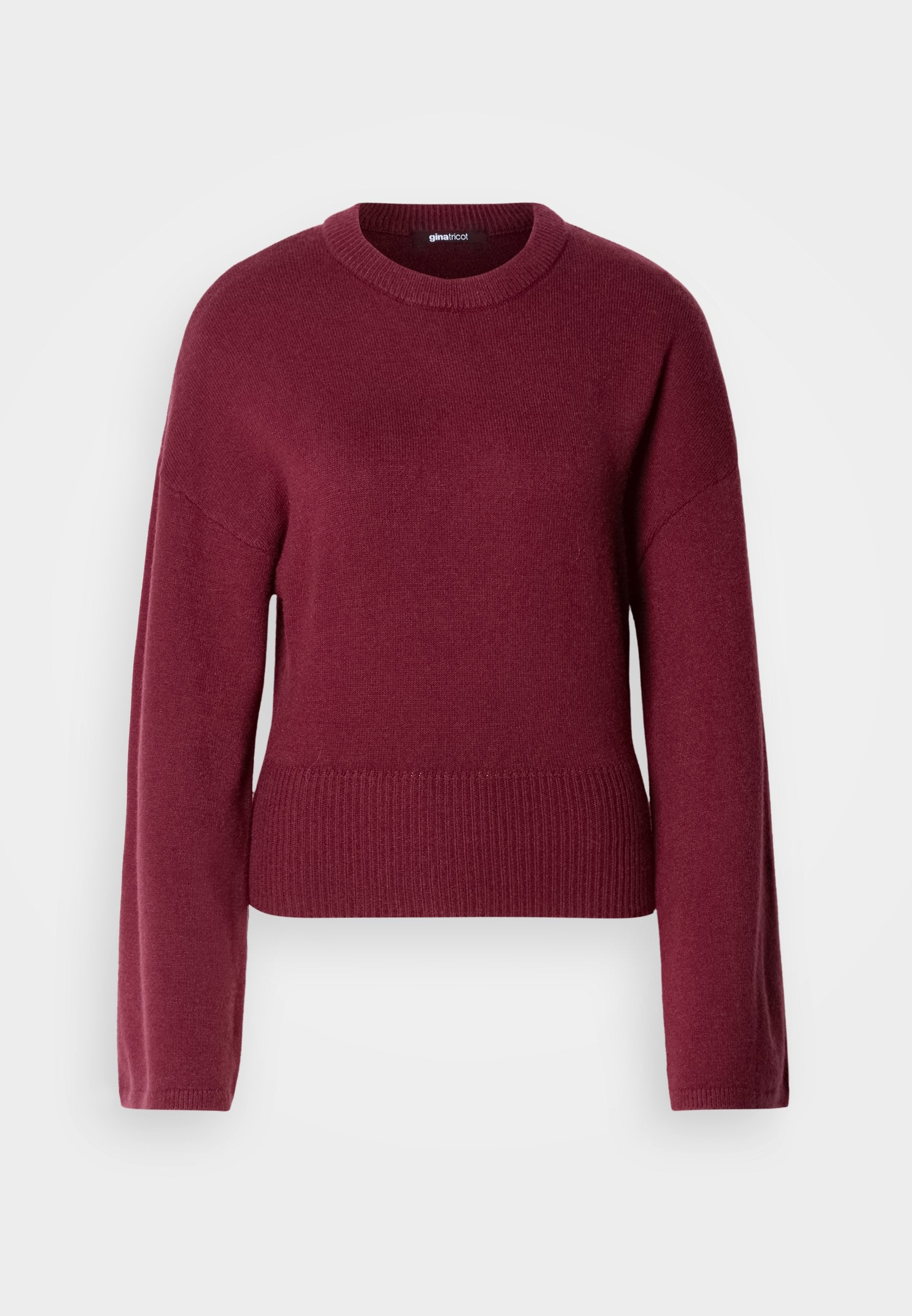 Burgunderfarbener Strickpullover mit rundem Ausschnitt, langen Ärmeln und geripptem Saum. Der Stoff wirkt weich und strukturiert.