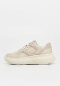 Beiger Sneaker aus Wildleder und Leder mit perforierten Details, Schnürung vorn und dicker, strukturierter Sohle, seitlich auf weißem Hintergrund dargestellt.