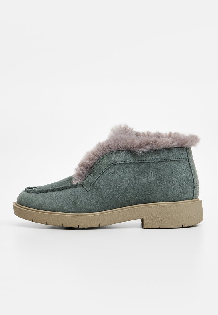 Wildleder-Ankle Boots in einem gedeckten Grünton mit grauem Kunstpelzbesatz, runder Spitze und einer strukturierten beigen Gummisohle. Einfache Nahtdetails an den Seiten.