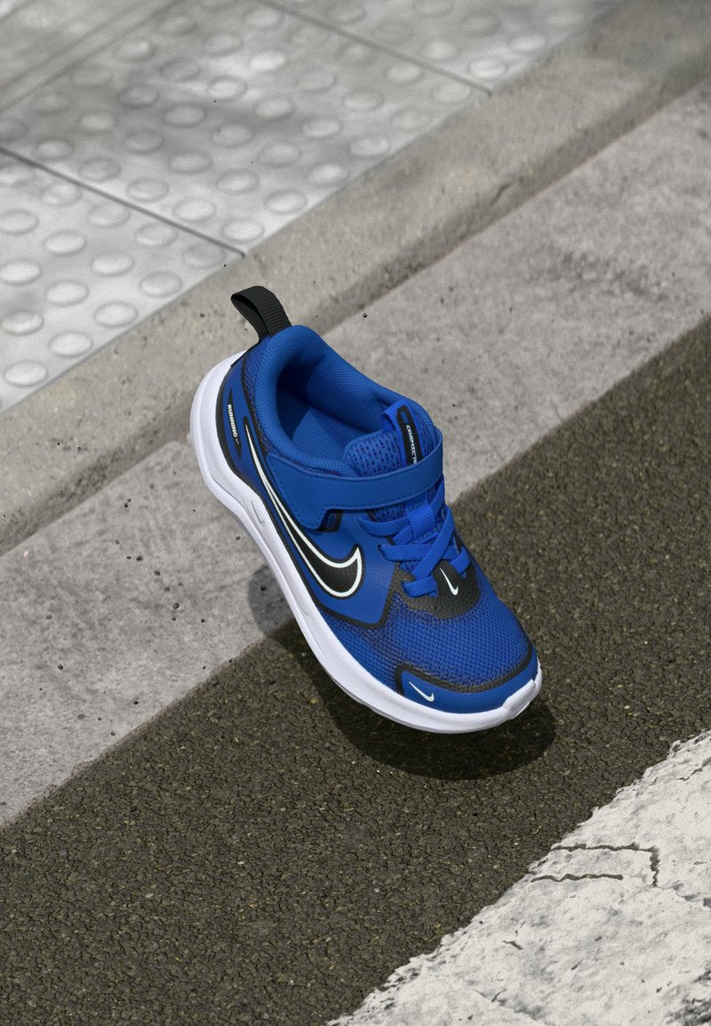 Blaue Sportschuh aus Mesh und Gummi, mit schwarzen Akzenten, einem sicheren Riemen und einer weißen Sohle mit strukturierten Mustern.