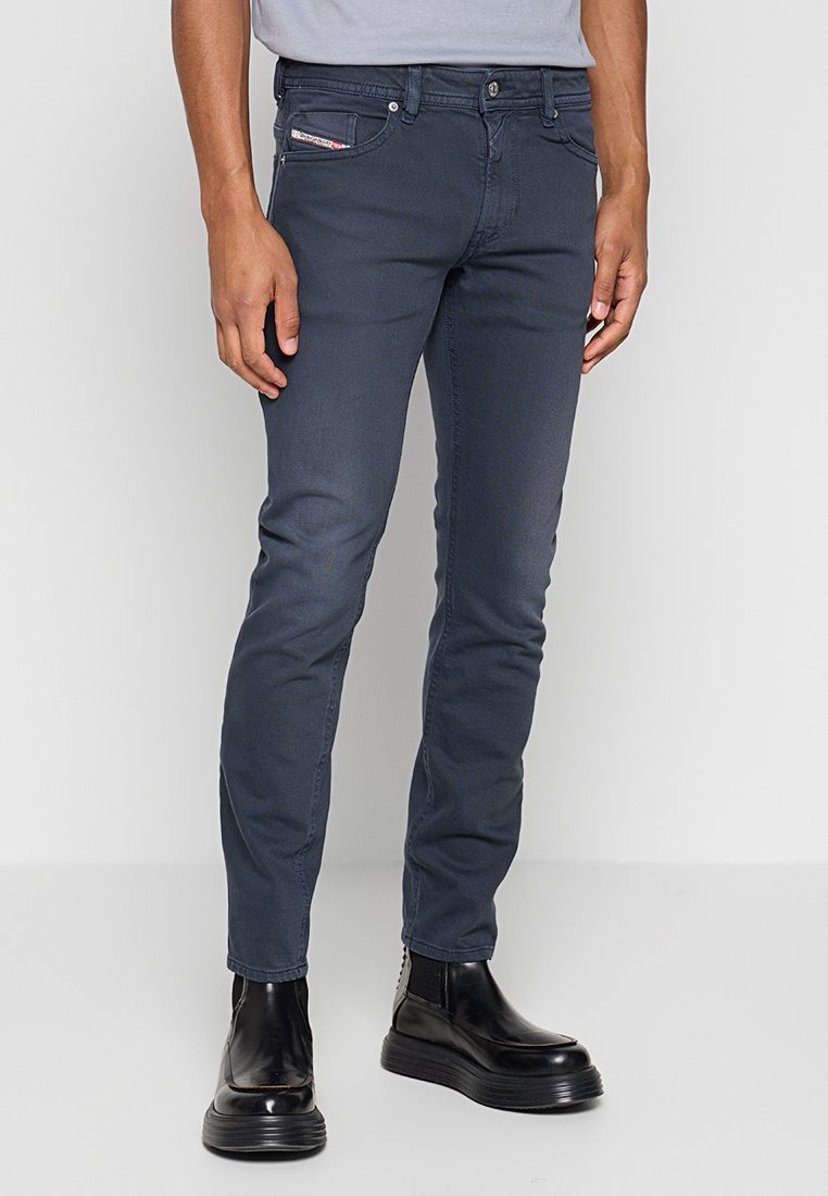 Dunkelgraue Slim-Fit-Jeans aus Denim, mit klassischem Fünf-Taschen-Design und subtilen Stichdetails, kombiniert mit schwarzen Knöchelstiefeln.