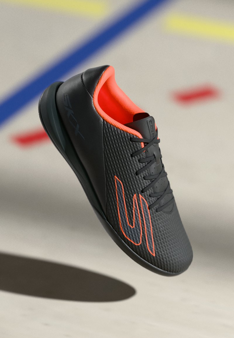 Schwarzer Sportschuh mit strukturiertem Obermaterial, neonorangefarbenen Akzenten und Schnürsenkeln. Verfügt über eine kurvenförmige Form und eine gepolsterte Sohle für Unterstützung.