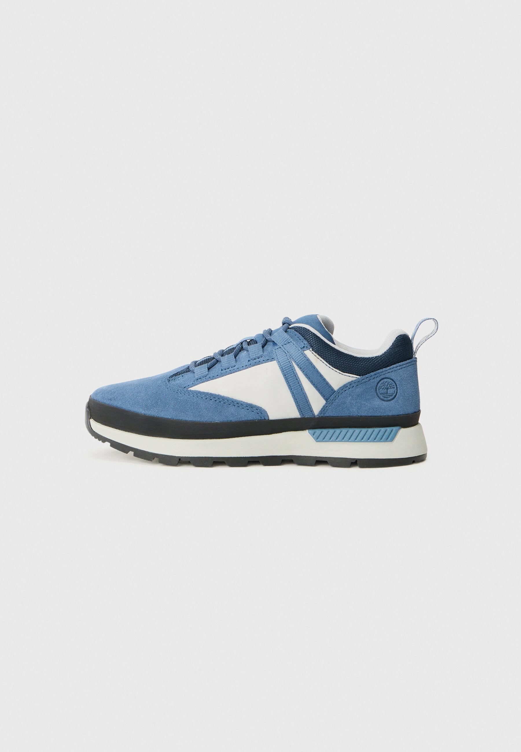 Seitenansicht eines blau-weißen Sneakers mit schwarzer Sohle und Schnürsenkeln auf einem einfarbigen Hintergrund.