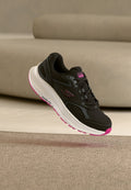 Schwarzer Sportschuh mit einem Obermaterial aus Mesh, weißer und pinker Sohle sowie strukturierten Akzenten. Verfügt über Schnürsenkel und ein Logo an der Seite.