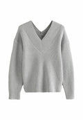 Grau gerippter Strickpullover mit tiefem V-Ausschnitt und abgesenkten Schultern, der eine strukturierte Optik und eine lockere Passform aufweist.