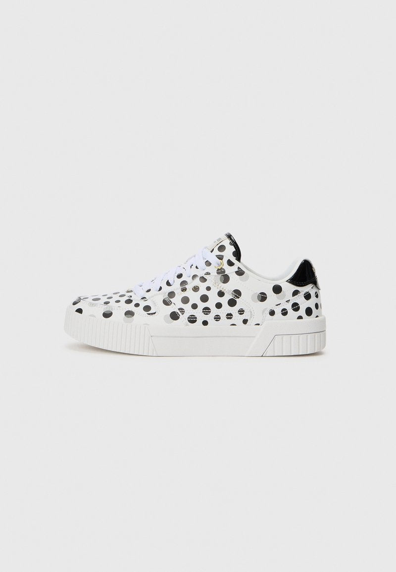 Weiße Sneaker mit niedriger Form, schwarzen Punkten, weißen Schnürsenkeln, dicker Sohle und glänzendem schwarzen Fersenabsatz vor einem schlichten Hintergrund.