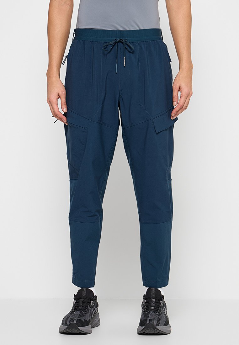 Marineblaue, leichte Hose mit elastischem Bund, Kordelzug, Cargotaschen und zulaufenden Beinen. Strukturierter Stoff mit glatter Oberfläche.
