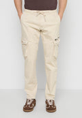 Beige Cargohosen mit Kordelzug in der Taille und mehreren Taschen, getragen mit braunen Sneakers und einem dunkelbraunen Hemd.