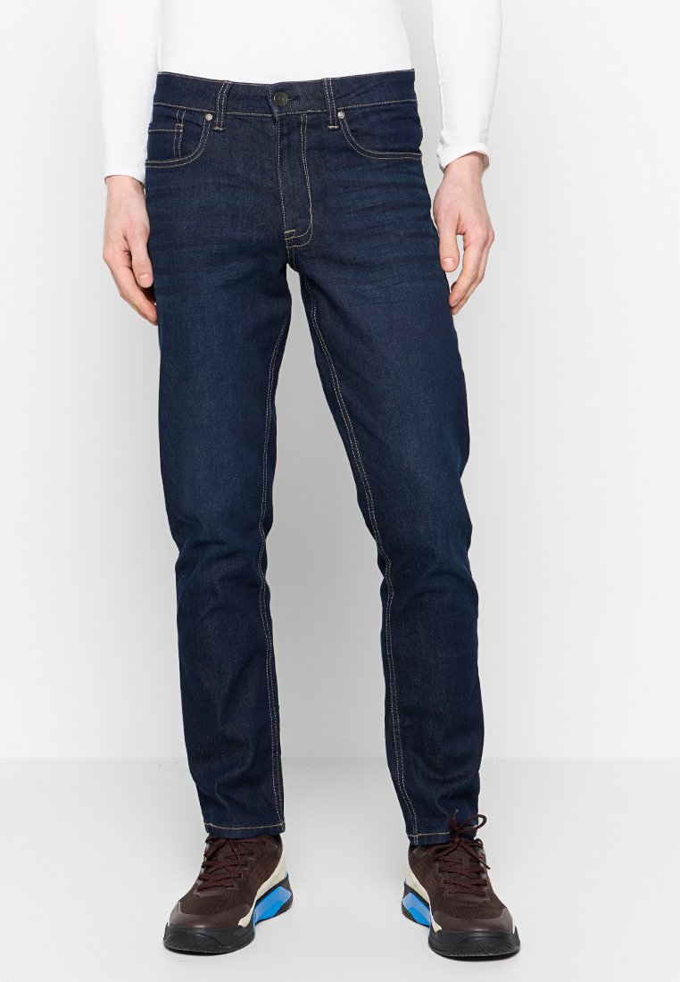 Dunkelblaue Jeans aus Denim mit schmaler Passform, kontrastierenden Nähten, Fünf-Taschen-Design und einem Knopfverschluss am Bund.
