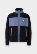 Fleecejacke mit hohem Kragen, schwarzer Körper und hellblauen oberen Teilen, mit Reißverschluss und zwei seitlichen Taschen.