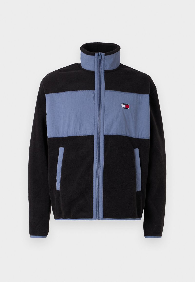 Fleecejacke mit hohem Kragen, schwarzer Körper und hellblauen oberen Teilen, mit Reißverschluss und zwei seitlichen Taschen.