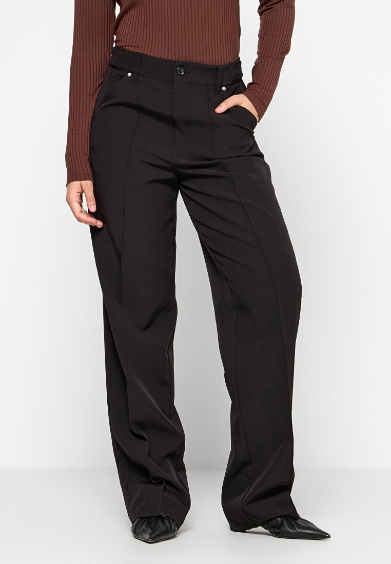 Schwarze weite Hose aus einem glatten Stoff, mit hoher Taille, Fronttaschen und dezenten Steppnähten.