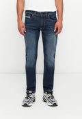 Ein Mann trägt blaue Slim-Fit-Jeans und weiße Sneakers mit schwarzen Schnürsenkeln und steht vor einem schlichten weißen Hintergrund.
