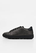 Schwarzer flacher Ledersneaker mit schwarzen Schnürsenkeln und strukturierter Gummisohle, seitlich auf weißem Hintergrund dargestellt.