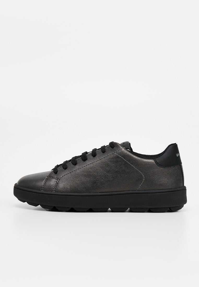 Schwarzer flacher Ledersneaker mit schwarzen Schnürsenkeln und strukturierter Gummisohle, seitlich auf weißem Hintergrund dargestellt.