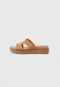 Helle Ledersandalen mit zwei sich überkreuzenden Riemen und einer dicken Plattformsohle. Sanfte Textur mit subtiler Nahtdetails entlang der Kanten.